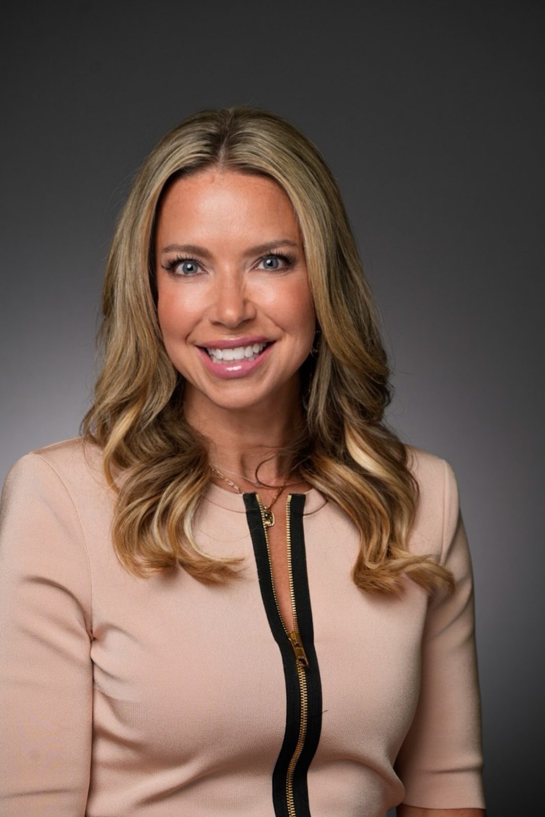 Studio headshot of Kate Willis in a blush top on a grey backdrop